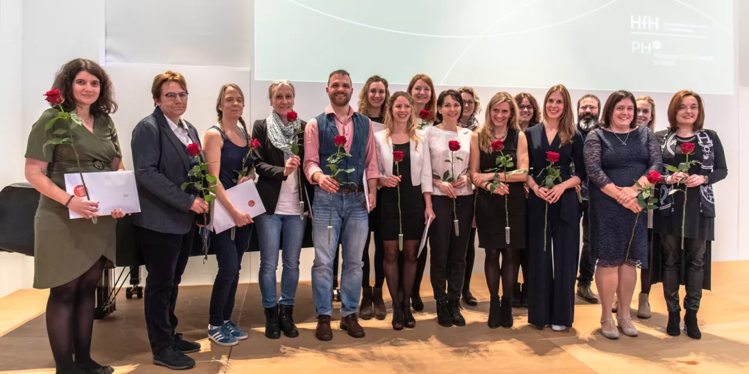 Gruppenbild: Absolventinnen und Absolventen des Masterstudiengangs Schulische Heilpädagogik halten ihr Diplom plus Rose; feierlicher Anlass; stehen auf Bühne (Foto: PHSG); 
